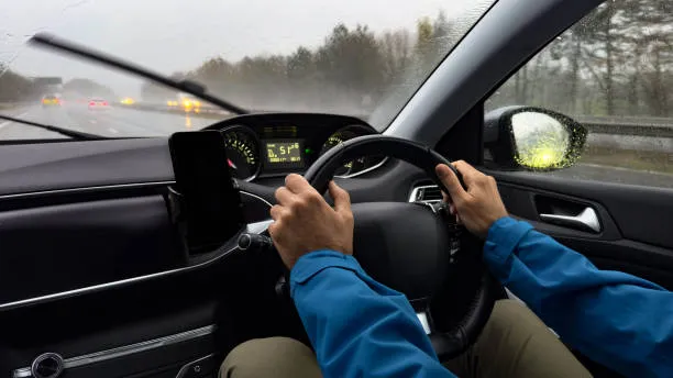 Hands on the steering wheel, driving on a wet motorway
